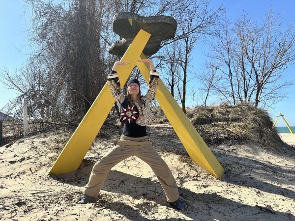 Melissa doing Shaolin Standing on a beach in front of yellow triangle.
